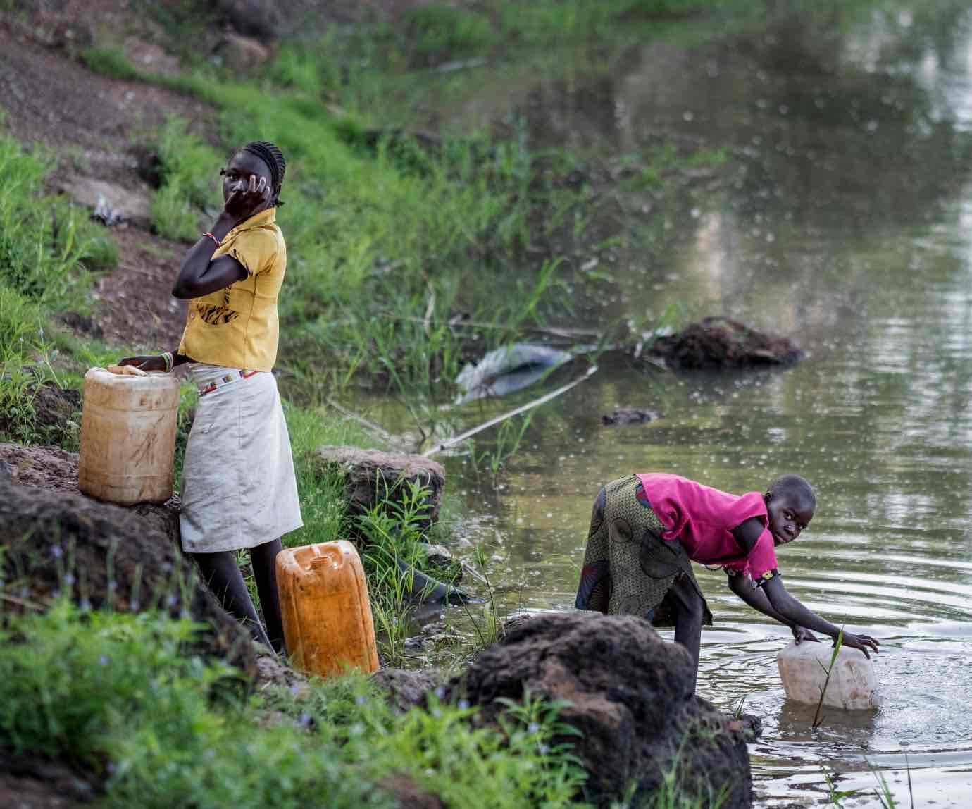 A girl gets dirty water from a river.