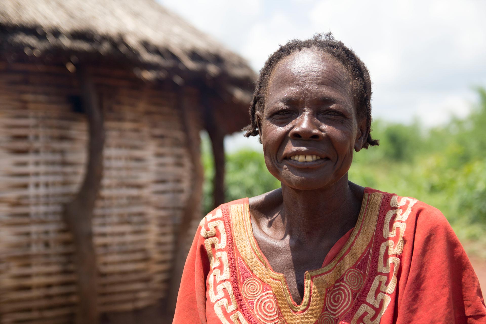 Mary stands outside her hut